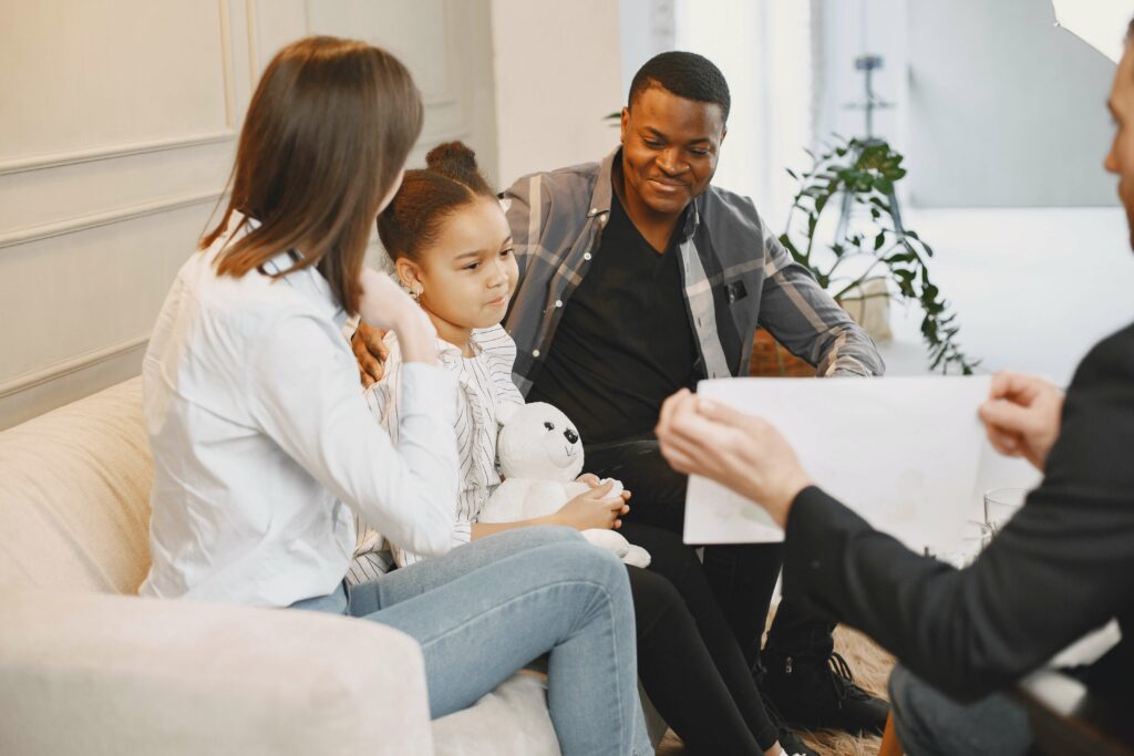 Little girl sitting between her smiling parents while a child behavioral therapist asks a question