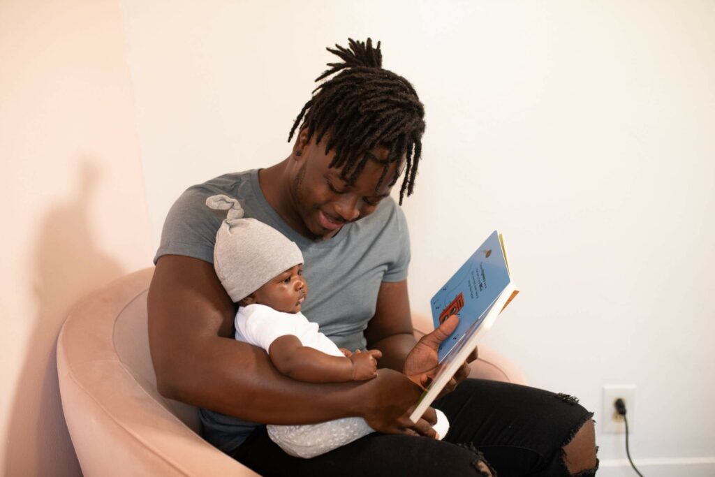 Father holding his baby on his lap while reading a board book